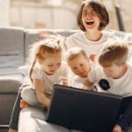 Mamá agotada sosteniendo la carga mental de la crianza neurodivergente mientras sus hijos juegan cerca